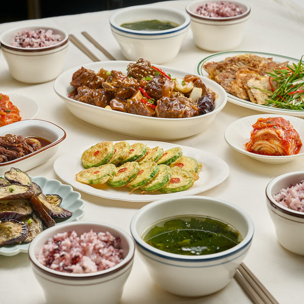 A Korean home-style table with rice, seaweed soup, braised short ribs, and assorted banchan side dishes