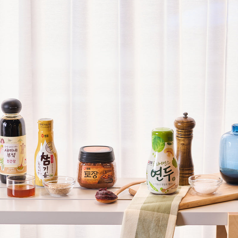 Korean pantry staples including soy sauces, doenjang, sesame oil and Yondu on a kitchen table