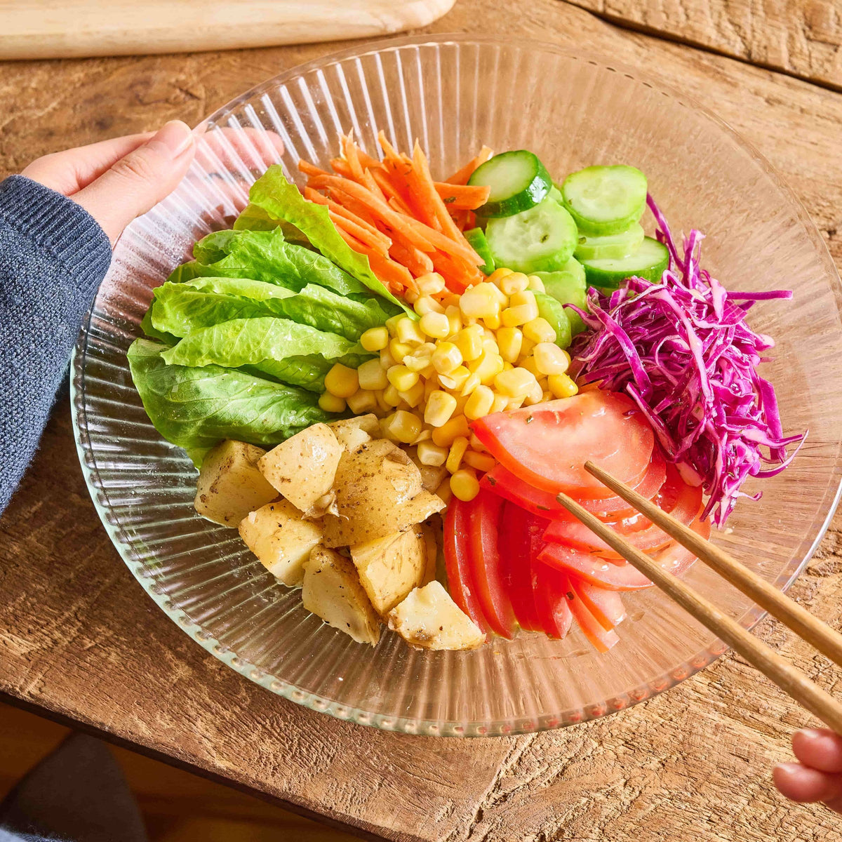 Colorful plant-based bowl with lettuce, cucumber, corn, potatoes, tomato and red cabbage